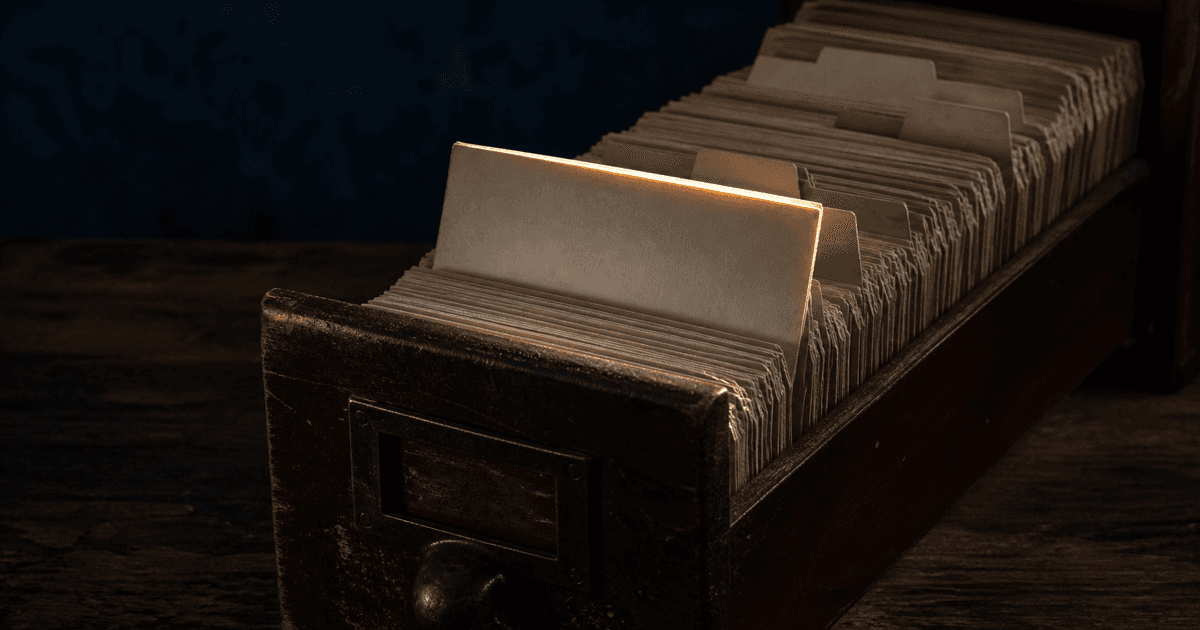 Open card catalog drawer with one blank index card lifted from the row
