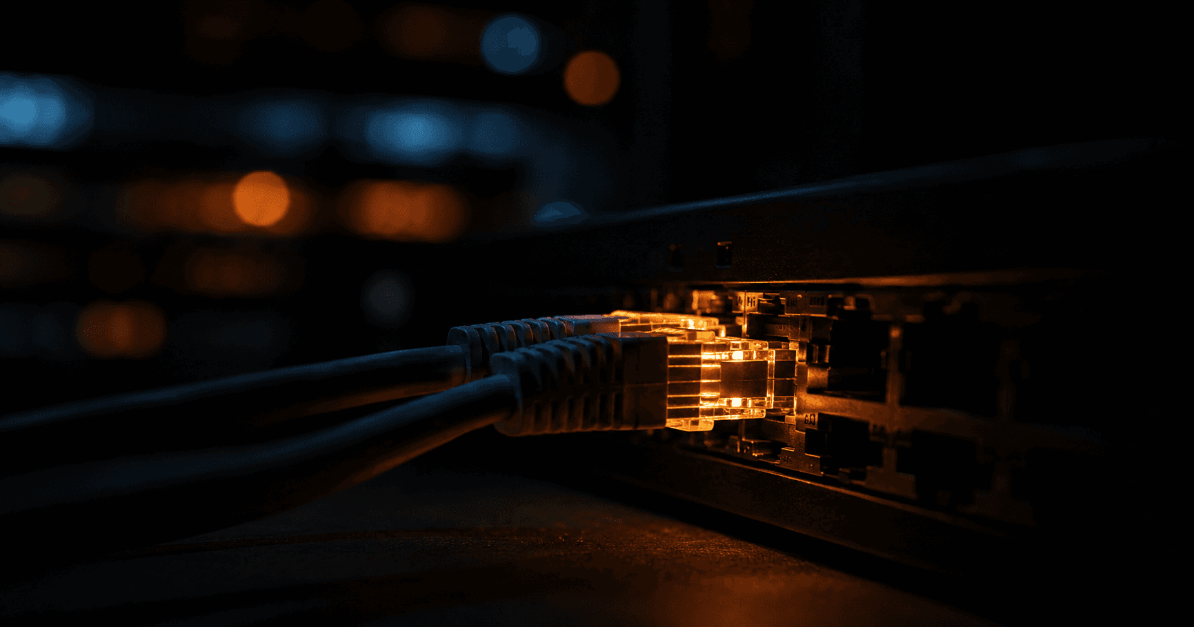 Close-up of ethernet cables plugged into a dark network switch, dramatic amber side lighting